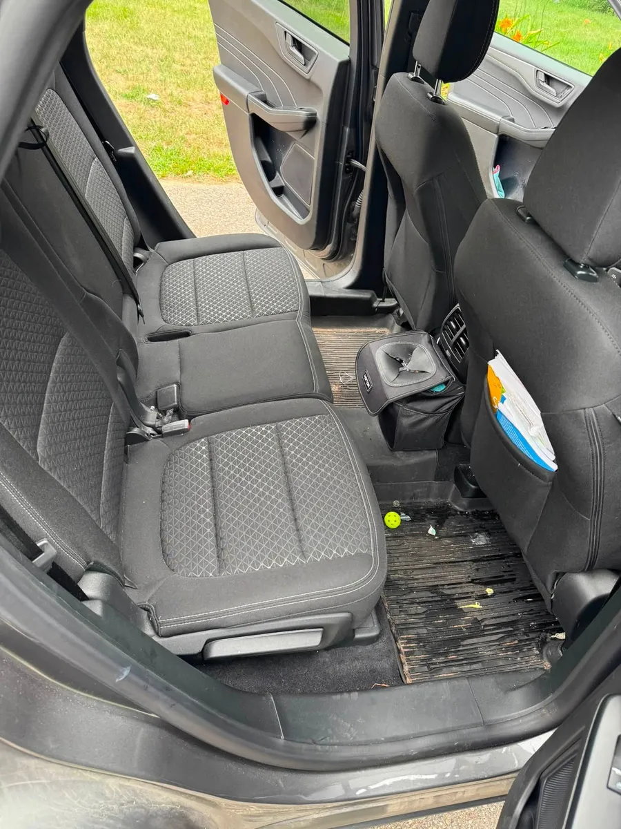 Rear vehicle seating before detailing with visible debris on the carpet